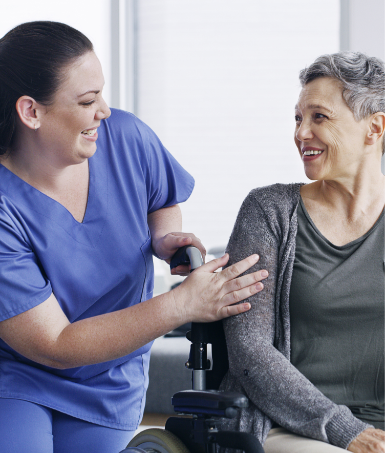 Nurse smiling at older woman seated in wheelchair